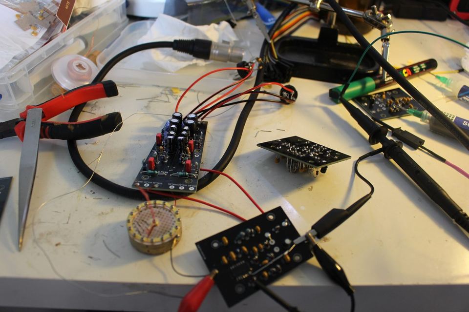 L’établi pendant les essais : cartes nues, pinces crocodile, sonde et capsule reliées par des fils.